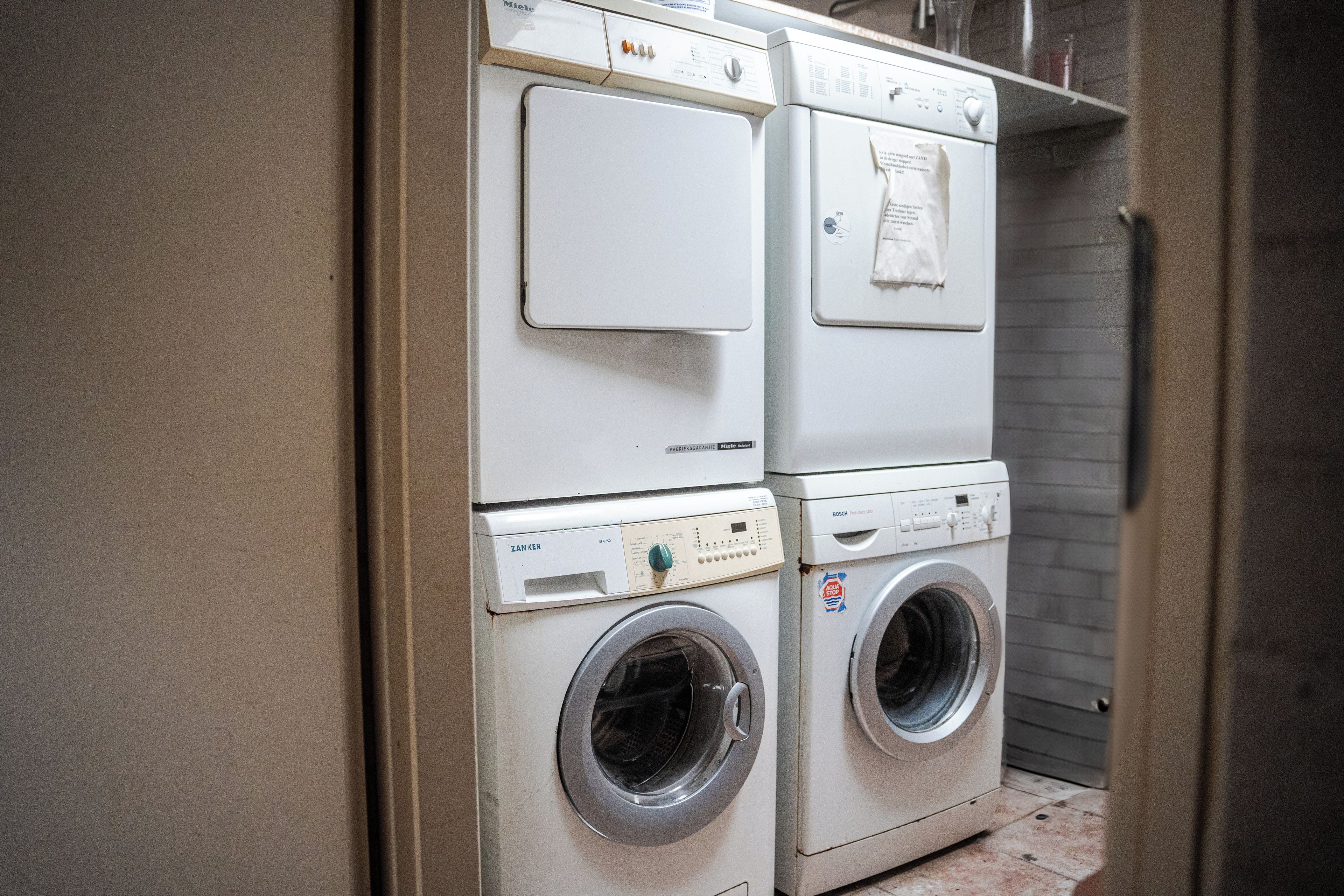 A laundry room with two stacked washing machines and a dryer.