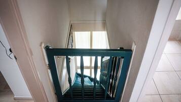A staircase with a wooden handrail and a metal railing, leading to a room with a window.