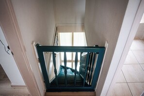 A staircase with a wooden handrail and a metal railing, leading to a room with a window.