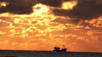 A ship on the water during sunset with clouds in the sky.
