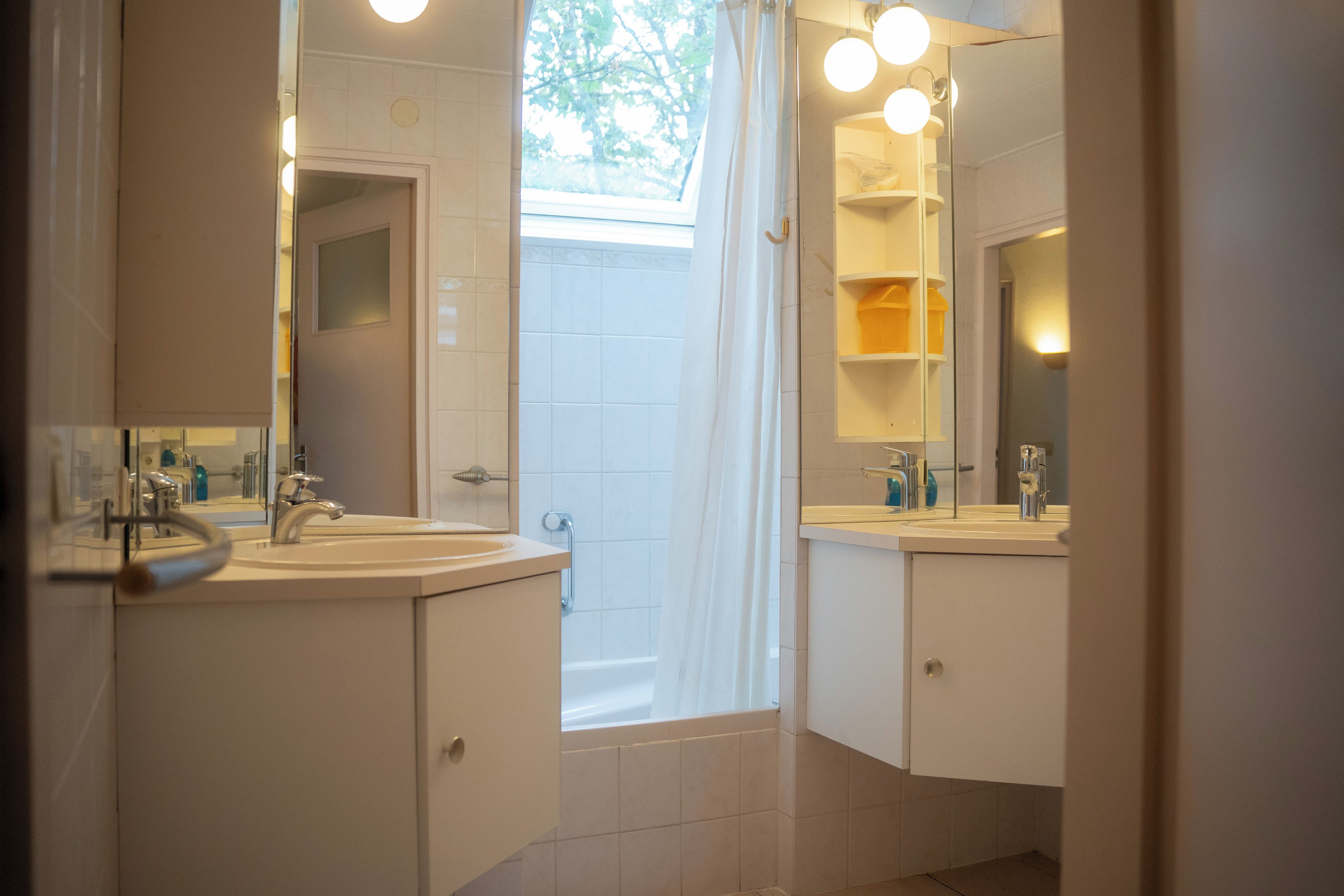 A bathroom with two sinks, a shower, and a mirror.