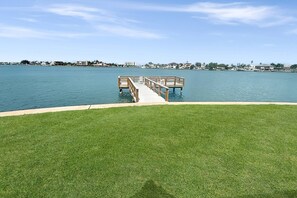 Un área verde con un muelle de madera que se adentra en un cuerpo de agua.