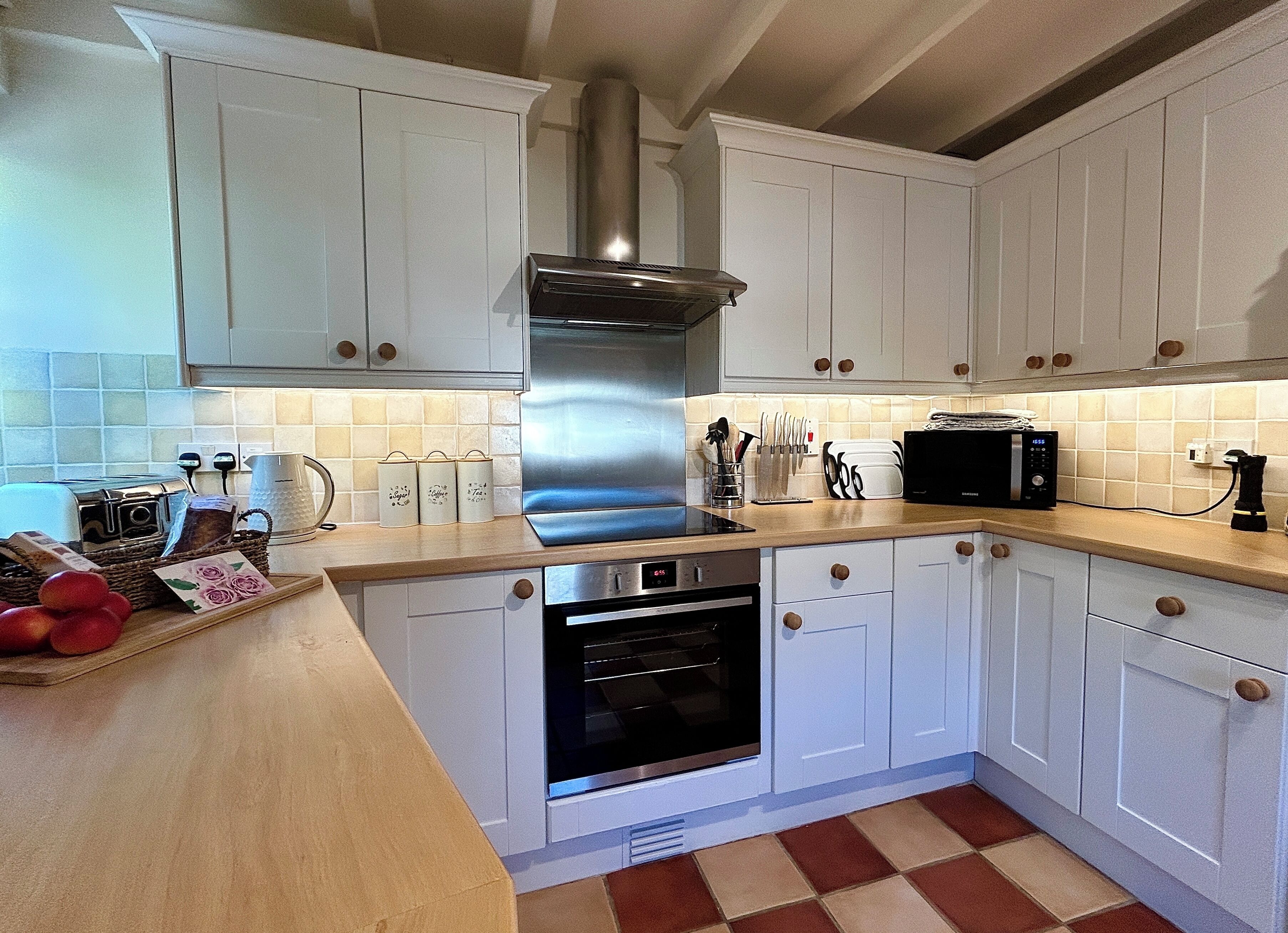 A modern kitchen with white cabinets, stainless steel appliances, and a tiled backsplash.