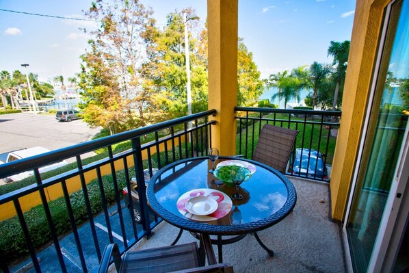 A balcony with a glass table, chairs, and a small plant.
