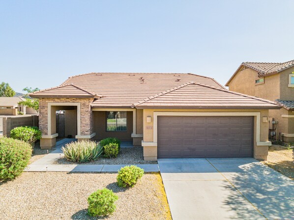 A residential house with a tiled roof, a garage, and a front yard with gravel and small bushes. - Phx Escape CENTRAL family pet friendly 4 bd sleeps 10 (Phoenix)