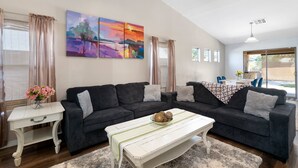A living room with a dark grey sectional sofa, a white coffee table, and a painting above the sofa. - Phx Escape CENTRAL family pet friendly 4 bd sleeps 10 (Phoenix)