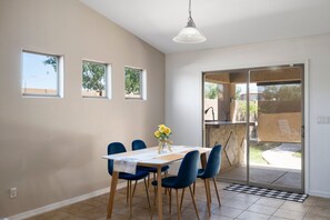 A dining area with a table and chairs, a vase with flowers, and a view through a sliding glass door to an outdoor space. - Phx Escape CENTRAL family pet friendly 4 bd sleeps 10 (Phoenix)
