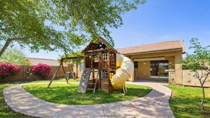 A playground with a slide and climbing structure, surrounded by a well-maintained lawn and a building with a tiled roof. - Phx Escape CENTRAL family pet friendly 4 bd sleeps 10 (Phoenix)