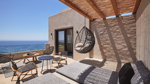 A terrace with a hanging chair, a sofa, and a table with chairs. - Noma Milos - Delmar Collection (Milos)