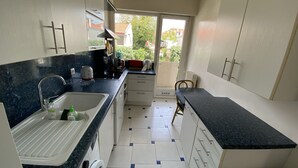 A compact kitchen with a sink, countertop, and a view of the outside. - T3 with parking 65 m2, 5 min walk from the beach. (Biarritz)