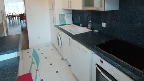 A modern kitchen with white cabinets, a black countertop, and a stainless steel range hood. - T3 with parking 65 m2, 5 min walk from the beach. (Biarritz)