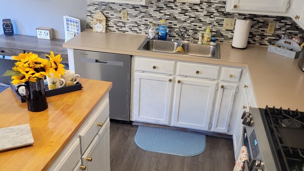 Cozinha moderna com armários brancos, pia de aço inoxidável e backsplash revestido de azulejos.