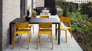 An outdoor patio with a dining table and chairs, a small sofa, and a potted plant. - Penny Williamsburg (Brooklyn)