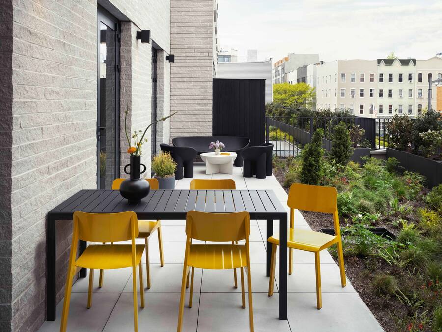 Un patio al aire libre con una mesa de comedor y sillas, un pequeño sofá y una planta en maceta.