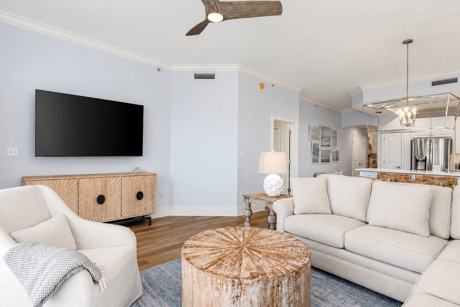 A modern living room with a flat-screen TV, a wooden cabinet, a round coffee table, and a sofa.