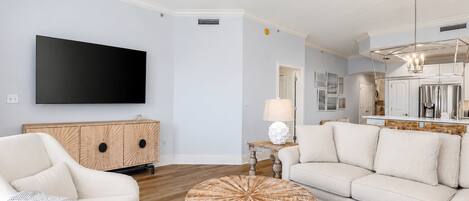A modern living room with a flat-screen TV, a wooden cabinet, a round coffee table, and a sofa.