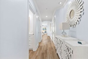A hallway with a white console table, a decorative mirror, and a patterned cabinet. - Sea View Serenity - 3BR/3BA Adagio Condo - Sleeps 8 - Community Pool View (Santa Rosa Beach)