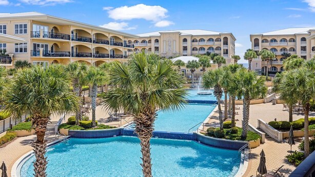 A hotel with a central swimming pool surrounded by palm trees and lounge areas. - Adagio - “Sea View Serenity” - Beautifully Redesigned 3 BR Unit Overlooking The Pool! (Santa Rosa Beach)
