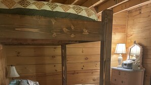 A wooden bunk bed with a quilted bedspread, a bedside lamp, and a dresser with a mirror and lamp. - Lyman Run Cabin - 2 miles from Lyman Run State Park - on ATV trails (Galeton)