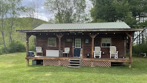 A rustic cabin with a porch, two chairs, a small table, and a bench. - Lyman Run Cabin - 2 miles from Lyman Run State Park - on ATV trails (Galeton)