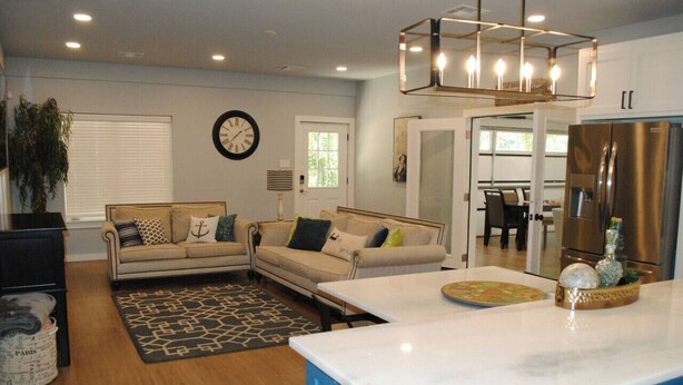 A modern living room with a sofa, a coffee table, and a kitchen area with a refrigerator.