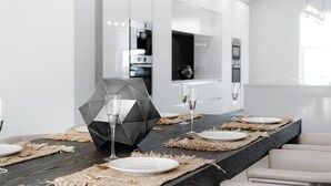 Ein zeitgemäßer Essbereich mit einem dunklen Holztisch, gedeckten Tellern, Gläsern und einem geometrischen Mittelstück.