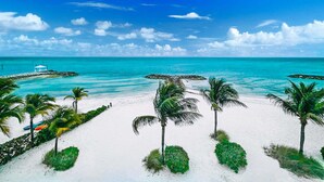 Ein Strand mit weißem Sand, türkisblauem Wasser und Palmen.