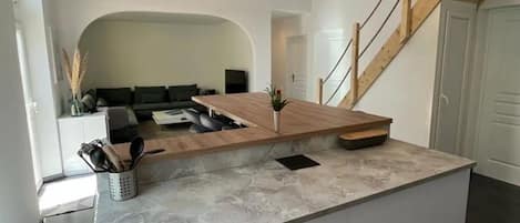 Eine moderne Küche mit einer zentralen Kochinsel, Holzbalken und einer Treppe.