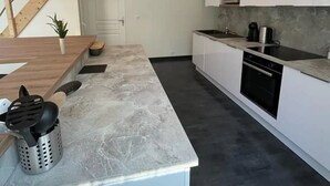 A modern kitchen with a marble countertop, a built-in oven, and a microwave. - Villa Avec Piscine en Plein Coeur de Bastia (Bastia)