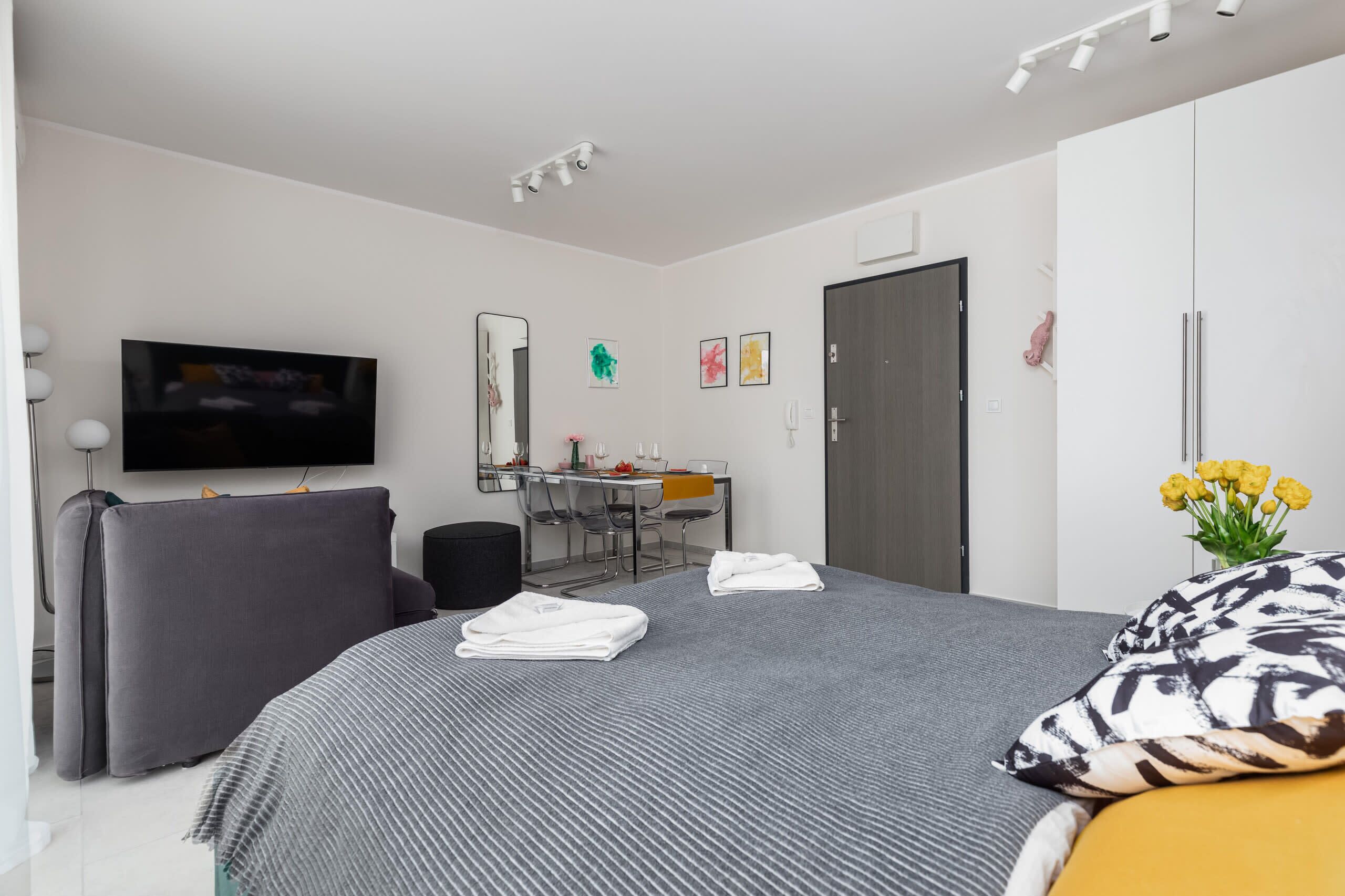 Een moderne hotelkamer met een bed, een bureau, een stoel, een televisie en een garderobe.