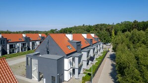 Un ensemble résidentiel moderne à l’architecture homogène, caractérisé par des toits recouverts de tuiles rouges et des façades grises.