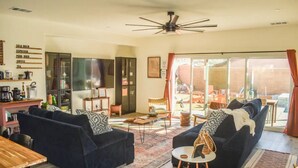 Una sala de estar moderna con sofás oscuros, una mesa de centro de madera y un ventilador de techo.