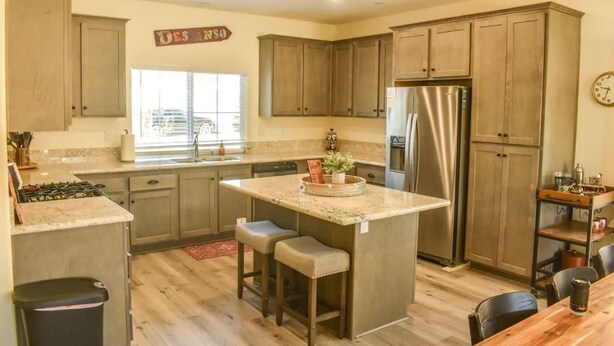 Una cocina con armarios de madera, un refrigerador de acero inoxidable y una isla central con taburetes.