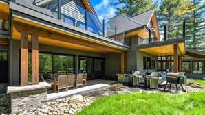 A modern house with a patio, outdoor seating, and a barbecue area.