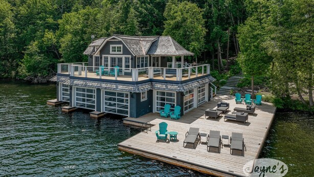 Una casa frente al agua con muelle, zona de estar al aire libre y un espacio cubierto.