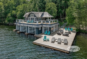 Ein Haus am Wasser mit einem Steg, Sitzgelegenheiten im Freien und einem überdachten Bereich.