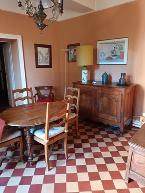 A dining area with a wooden table and chairs, a checkered floor, a wooden cabinet, and a chandelier.