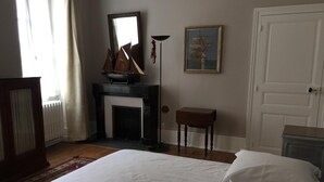 Ein Schlafzimmer mit Bett, Kamin, Tür und einem gerahmten Bild an der Wand.