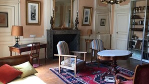 Ein traditionelles Wohnzimmer mit Kamin, einem runden Tisch und mehreren Sesseln.