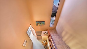 Un escalier avec une rampe en bois menant à un palier où se trouvent une petite table et un objet décoratif.