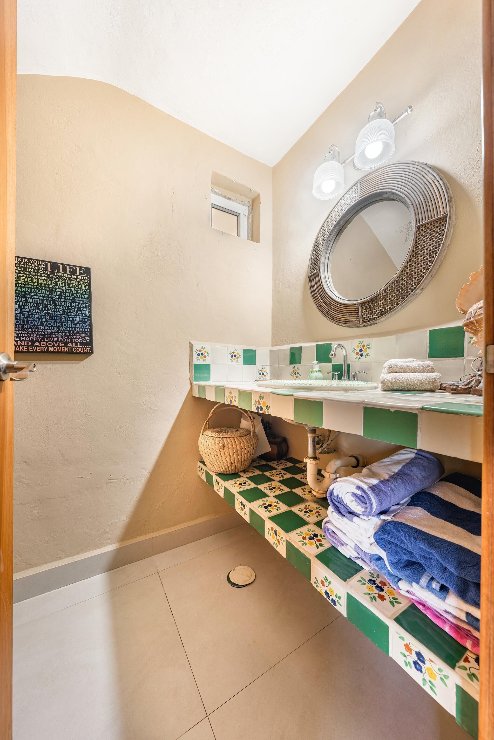 Une salle de bain équipée d’un lavabo, d’un miroir, d’un porte-serviettes et d’une citation inspirante sur le mur.