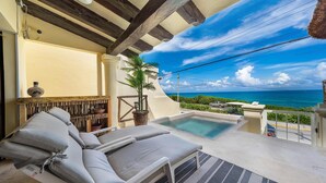 Un espace aménagé au bord de la piscine, avec des chaises longues, une petite piscine et une vue sur l’océan.