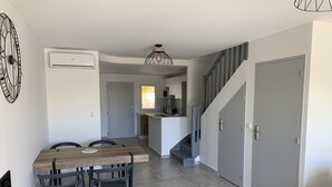 A modern kitchen with a built-in stove, a dining area with a wooden table and chairs, and a staircase leading to another level. - Maracuja 16, in the center of Orient Bay, beach 100m away (saint martin)
