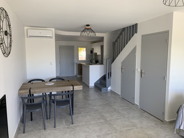 A modern kitchen with a built-in stove, a dining area with a wooden table and chairs, and a staircase leading to another level. - Maracuja 16, in the heart of Orient Bay, 100 meters from the beach (saint martin)