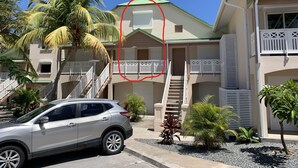 A two-story building with a green roof, white balconies, and a staircase leading to the upper floor. - Maracuja 16, in the center of Orient Bay, beach 100m away (saint martin)