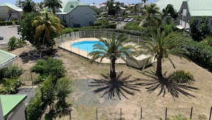 A residential area with a swimming pool surrounded by palm trees and a fenced yard. - Maracuja 16, in the center of Orient Bay, beach 100m away (saint martin)
