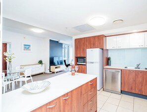 A modern kitchen with wooden cabinets, a white countertop, and stainless steel appliances.
