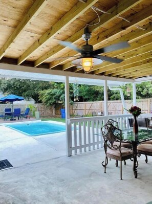 Relax by the pool in a serene backyard oasis with a ceiling fan overhead.