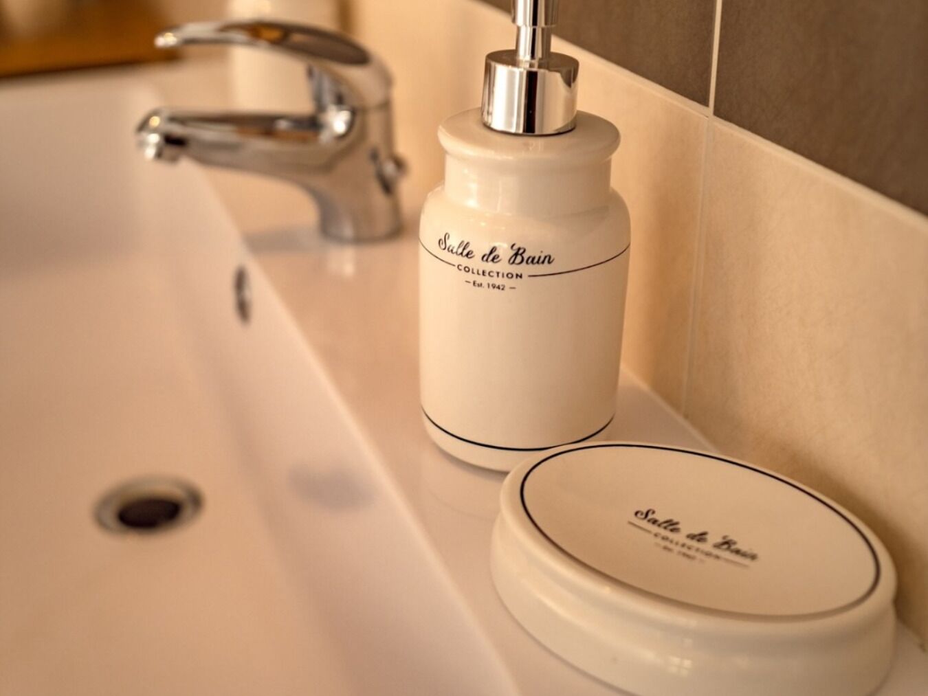 Un lavamanos con grifo y dispensador de jabón etiquetado como 'Salle de Bain Collection'.