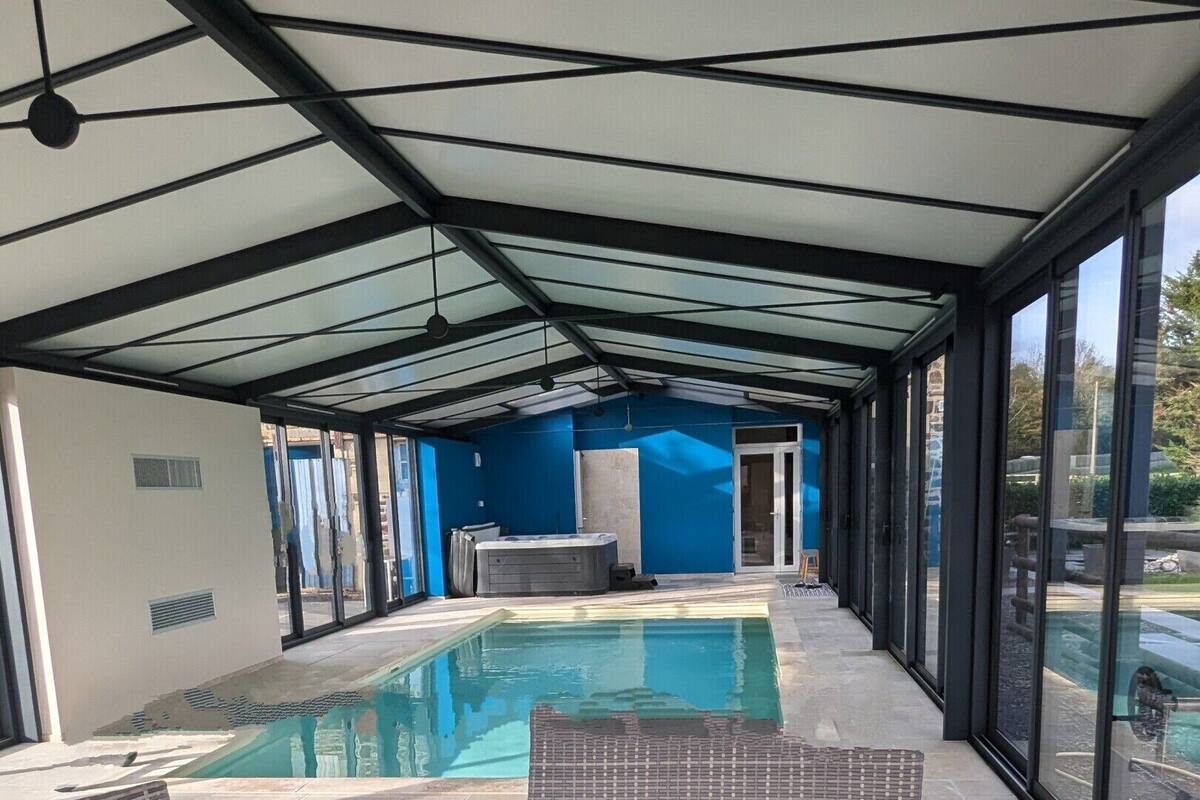 Un espacio exterior cubierto con piscina, mobiliario de mimbre y una mesa de vidrio.